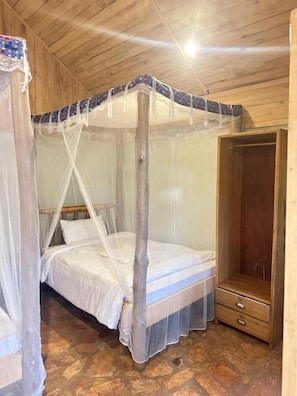 Una habitación con cama con dosel, un armario de madera y suelo de piedra.
