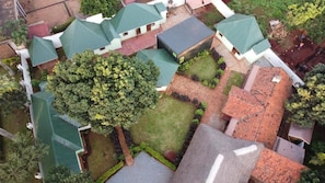 Vista aérea de una zona residencial con varias casas, techos verdes y un árbol central.