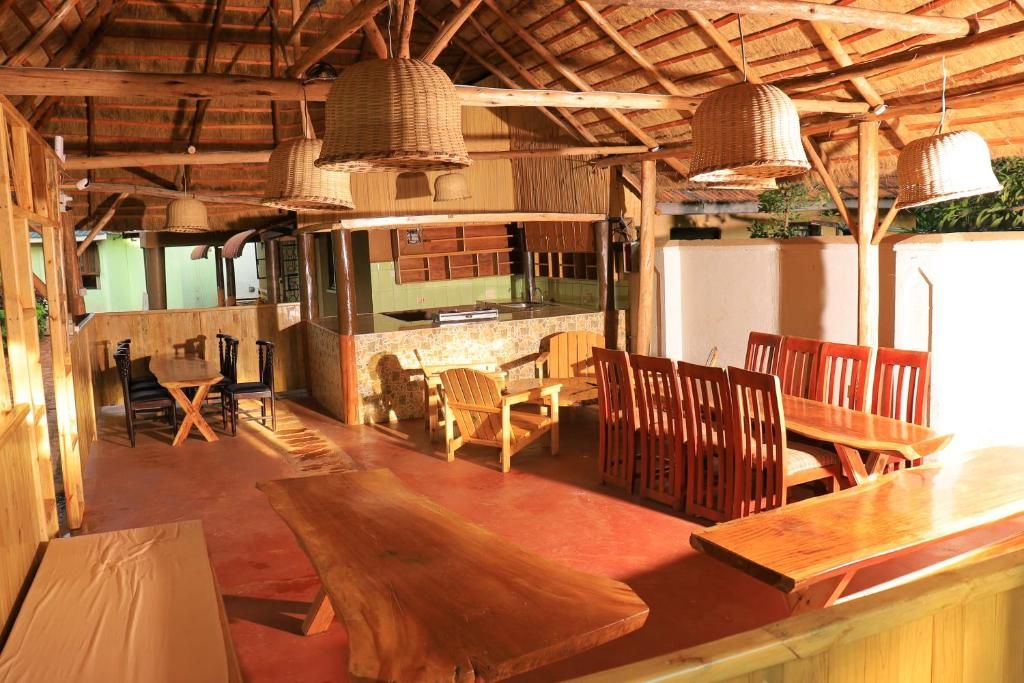 A rustic wooden interior with a bar area, wooden tables, and chairs, and a kitchen in the background.