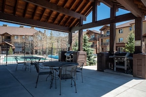 An outdoor patio with a pool, grilling area, and dining chairs. - Trailhead Lodges 711 | Walk Downtown, Hot Tub (Winter Park)