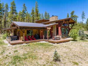 A cabin with a covered porch, outdoor seating, and a stone chimney. - Tabernash Retreat | 3BR, Hot Tub, Mtn Views (Tabernash)
