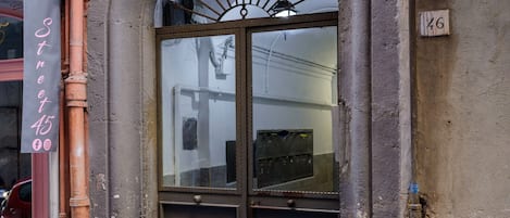 A building entrance with a large arched doorway, a sign above the door, and a number plaque on the wall.