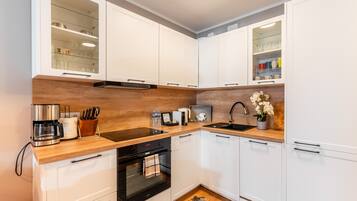 Una cocina moderna con armarios blancos, encimera de madera, horno integrado y un fregadero.