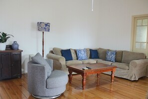 Un salon comprenant un canapé, un fauteuil, une table basse en bois et un lampadaire.