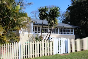 A residential house with a white picket fence, a garage, and a mailbox. - Charming cottage in the heart of Maleny. Two minute walk from the main street. (Maleny)