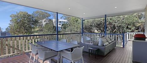 An outdoor deck with a table and chairs, a sofa, and a barbecue grill.
