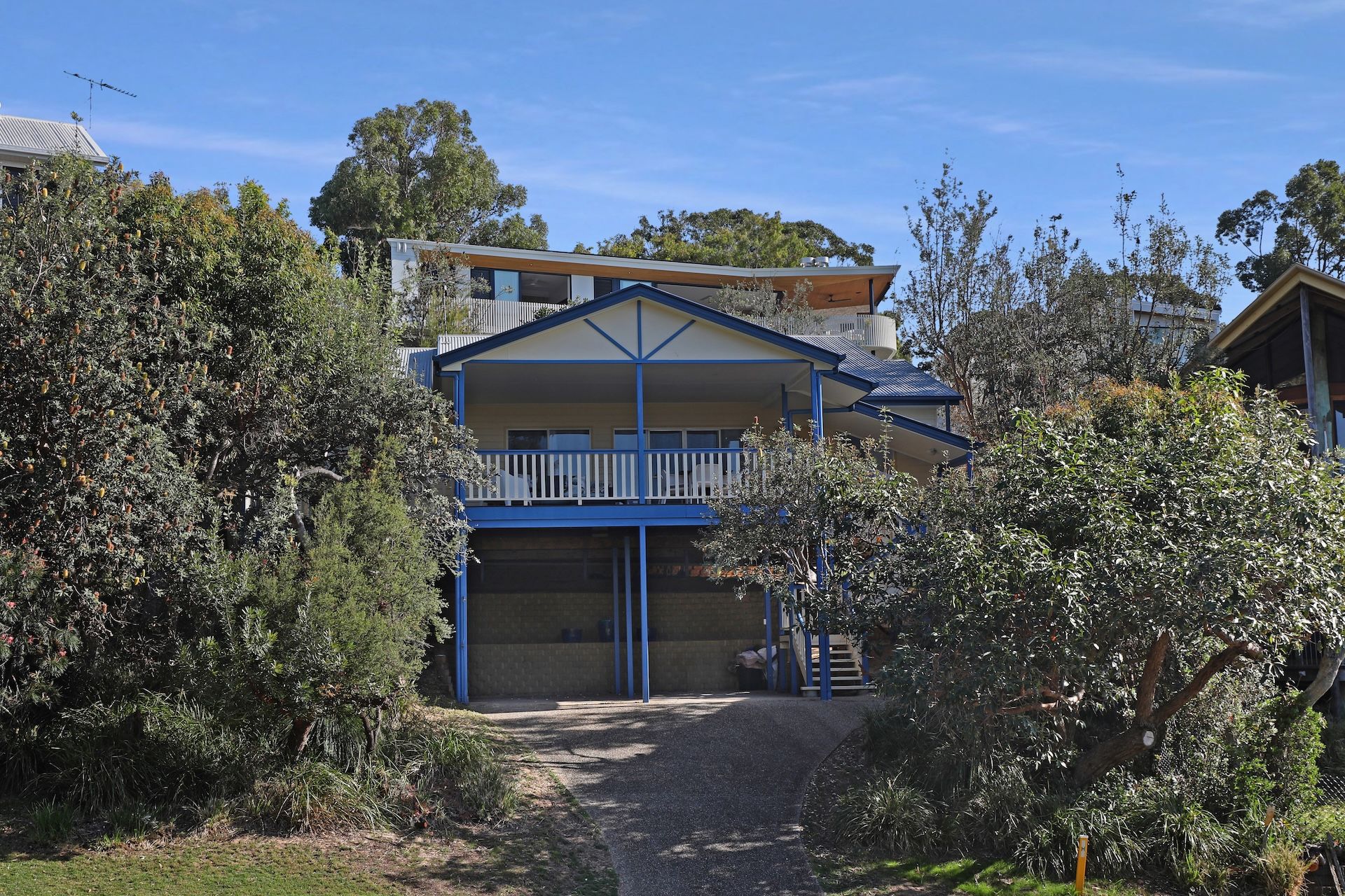 A two-story building with a balcony, surrounded by dense vegetation.