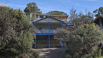 A two-story building with a balcony, surrounded by dense vegetation.