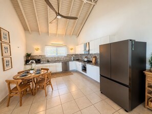 A modern kitchen with a central island, stainless steel appliances, and a ceiling fan. - New 5-bedroom family villa in Esmeralda-noord, just 3 minutes from Arashi Beach. Enjoy peaceful Salinja views, a beautiful private pool, natural stone details, a covered outdoor patio with BBQ, 5 king bedrooms, a full kitchen,and space for 10 Guests (Noord)