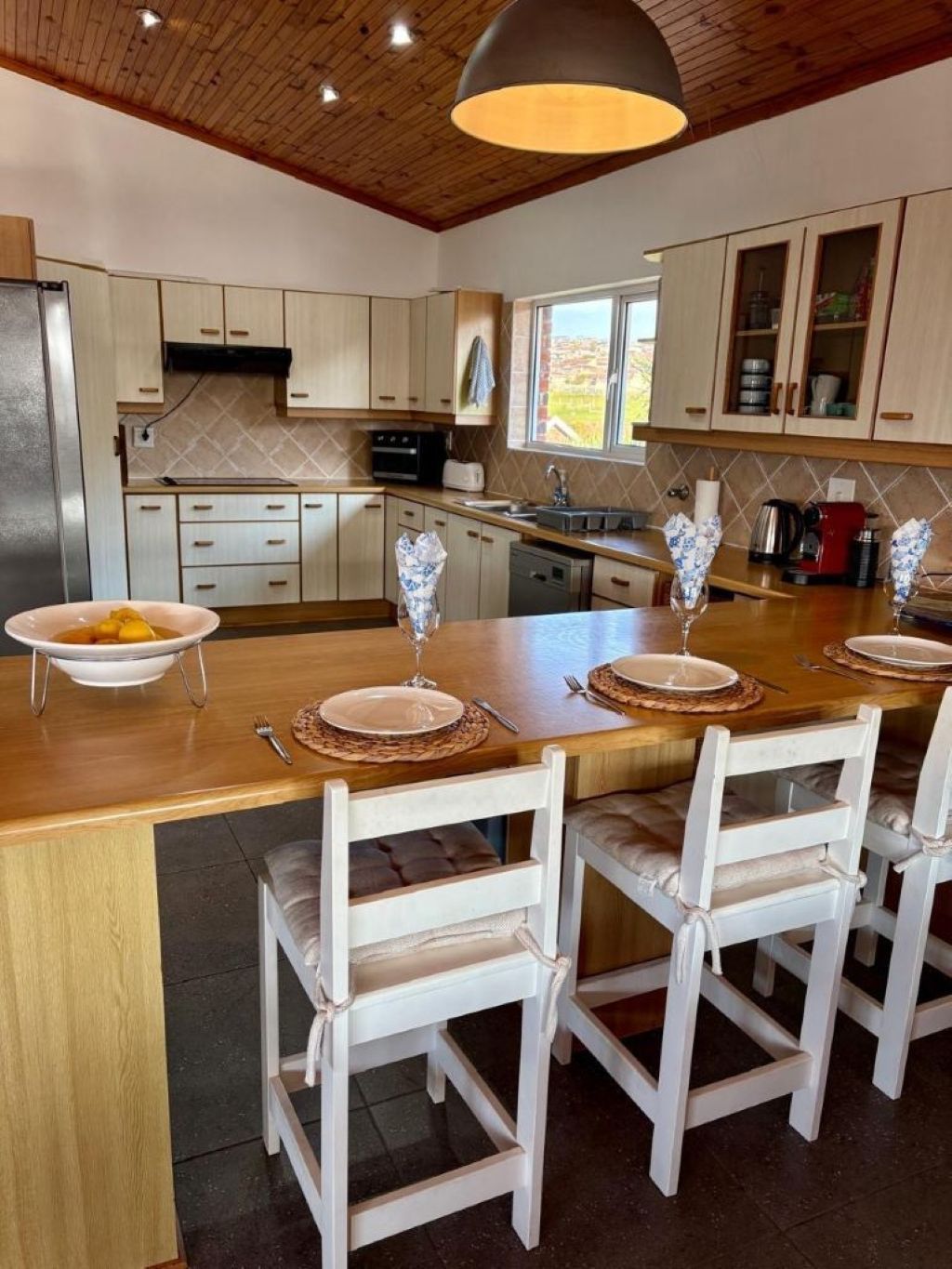 Une cuisine moderne avec un îlot central, des armoires en bois et une grande fenêtre.