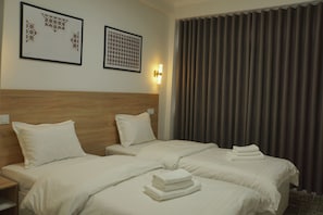 A hotel room with two beds, a headboard, a wall-mounted light, and a curtain. - Bogdon Hotel Samarqand (Samarkand)