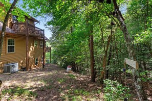 A wooden cabin with a deck, surrounded by dense forest. - Mountain Views & Fire Pit | Dog-Friendly Cabin (Warne)