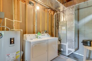 A laundry area with a washer and dryer, visible plumbing, and insulation materials. - Mountain Views & Fire Pit | Dog-Friendly Cabin (Warne)