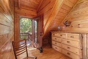 A wooden interior with a wooden chair, a dresser, and a door leading outside. - Mountain Views & Fire Pit | Dog-Friendly Cabin (Warne)