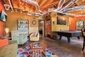 A cozy room with a dartboard, bookshelf, armchair, and pool table. - Mountain Views & Fire Pit | Dog-Friendly Cabin (Warne)