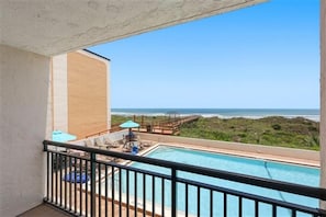 Ein Balkon mit Blick auf einen Pool und einen Strand.