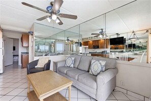 Ein moderner Wohnbereich mit einer Couch, einem Tisch und einem Deckenventilator.