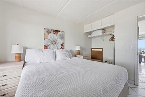 Ein Schlafzimmer mit einem großen Bett, zwei Nachttischen mit Lampen, einem Bild an der Wand und Blick nach draußen.