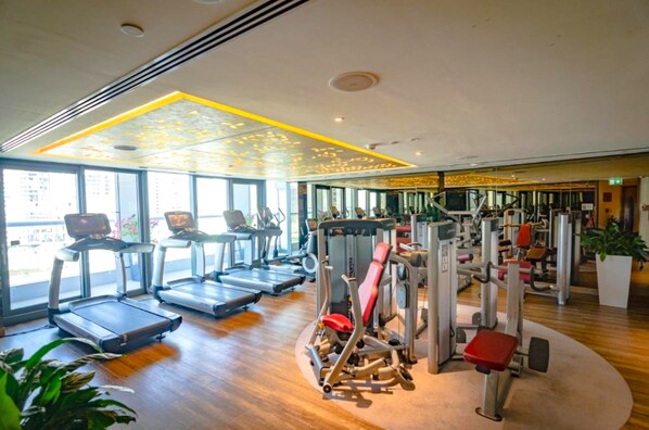 A gym with treadmills, weight machines, and large windows. - Sky Level 2BR with Harbour View, Just a Quick Drive to Downtown AttractionsSky Level 2BR with Harbour View, Just a Quick Drive to Downtown Attractions (Dubai)