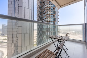 A balcony with a wooden table and benches, overlooking a cityscape with modern buildings. - Sky Level 2BR with Harbour View, Just a Quick Drive to Downtown AttractionsSky Level 2BR with Harbour View, Just a Quick Drive to Downtown Attractions (Dubai)