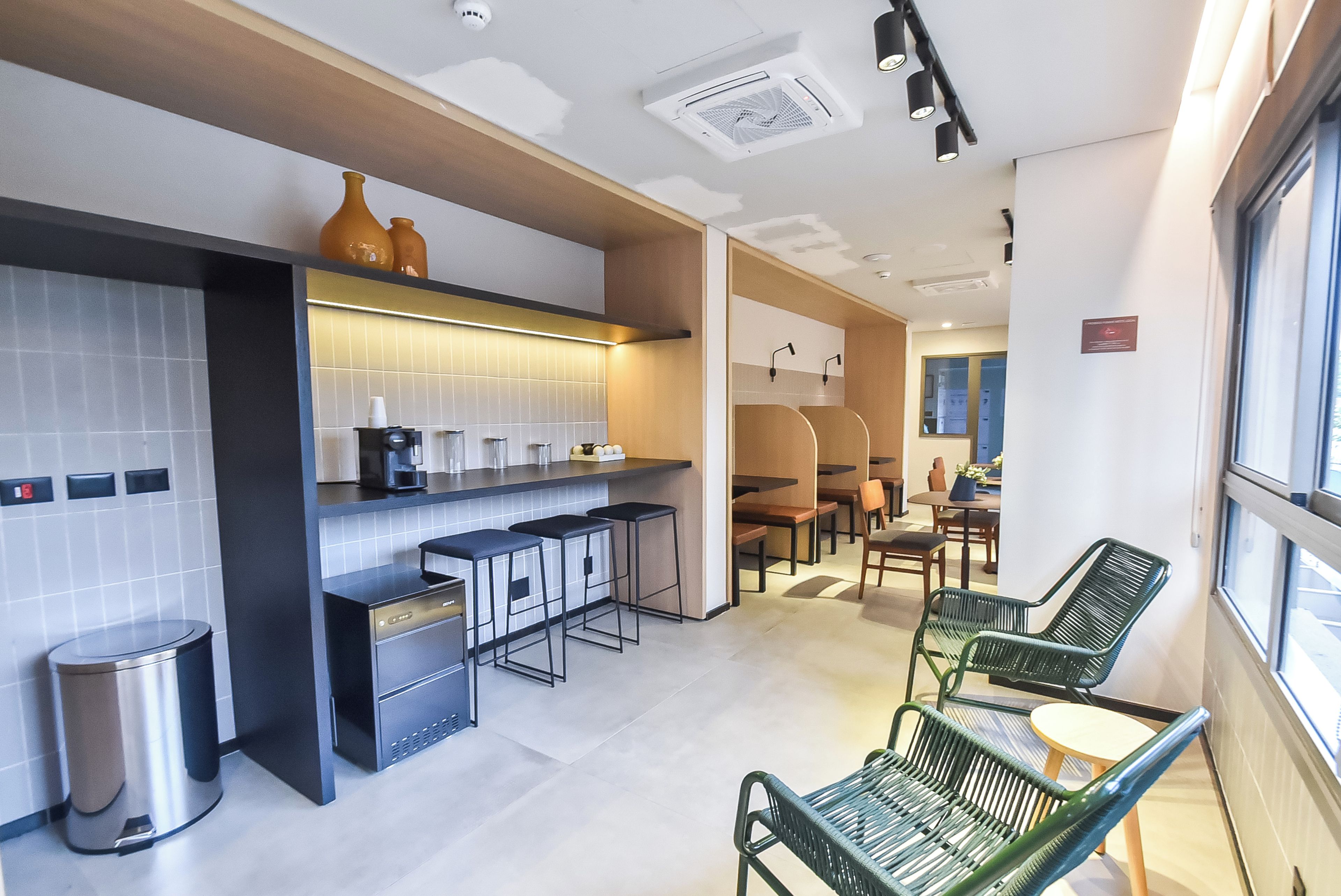 A modern kitchen with a coffee machine, a trash bin, and a seating area with chairs and a table.