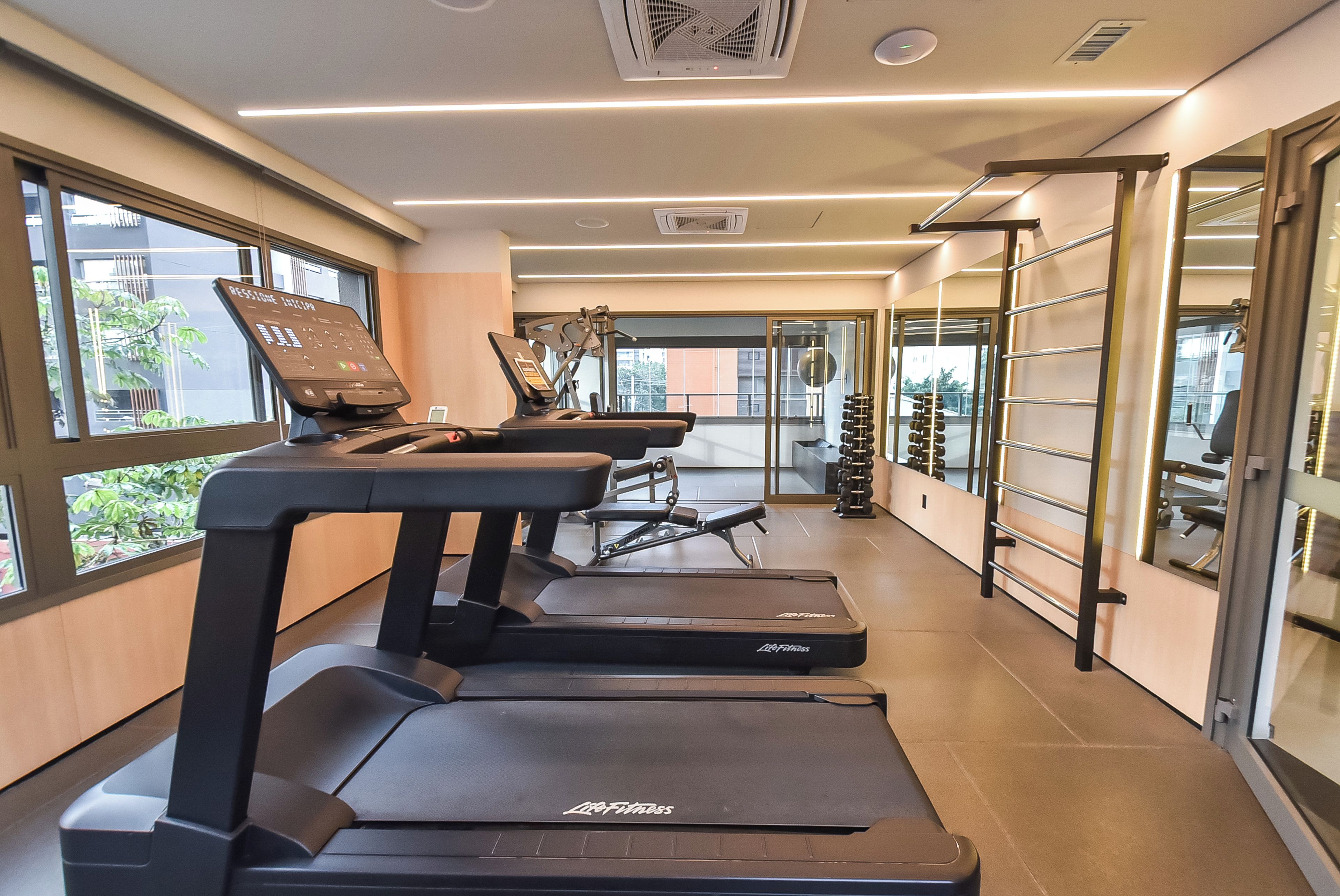 A gym with treadmills, weight machines, and a mirrored wall.