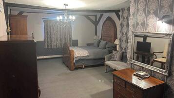 A bedroom with a bed, a dresser, a mirror, and a chandelier.