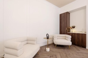 A modern living room with a sectional sofa, a small round table with a decorative item, and a wooden cabinet with a countertop. - La Maison Parliament by BQA (Budapest)