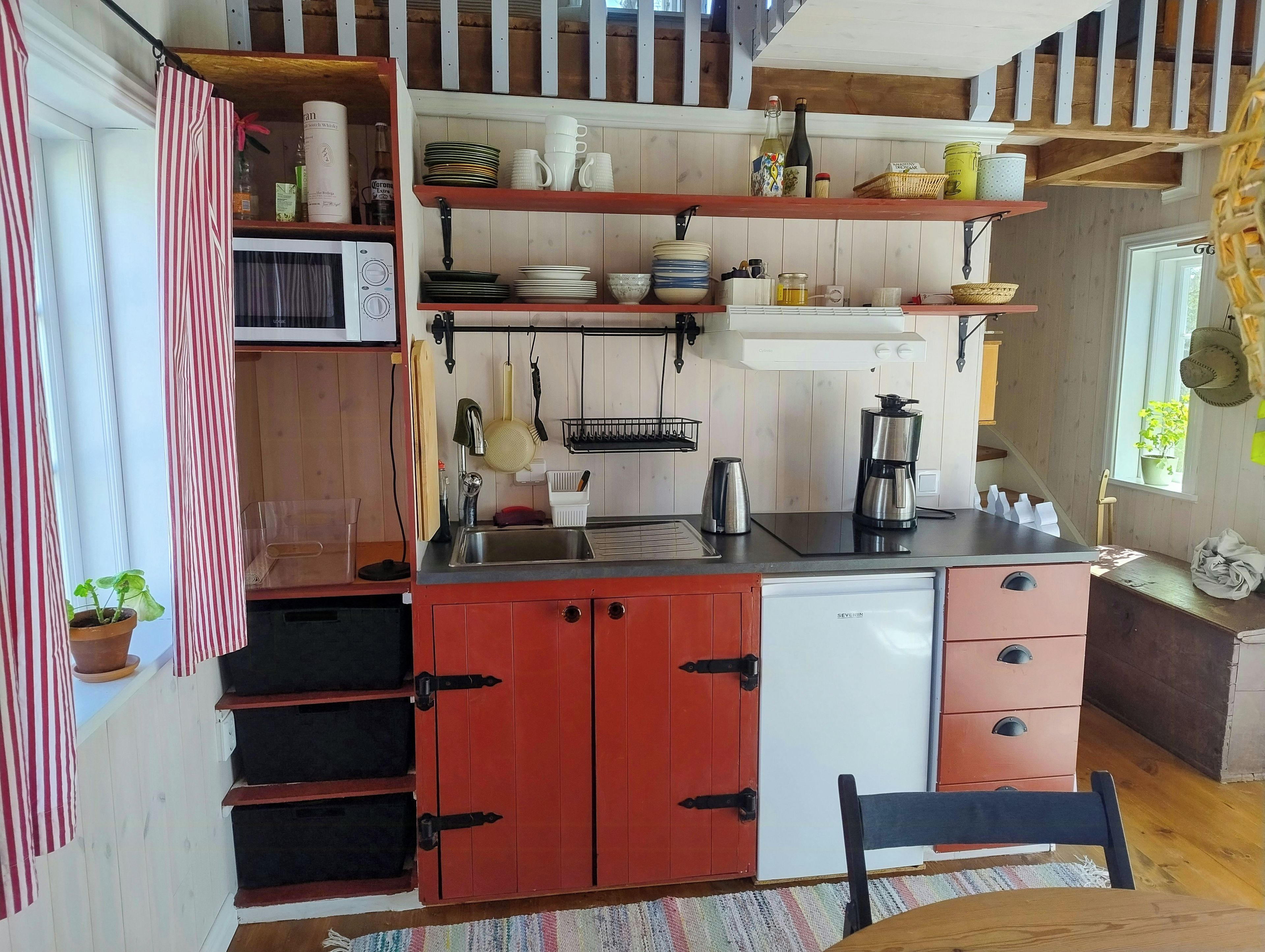 Cocina compacta con microondas, cafetera y refrigerador.