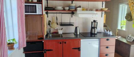 Cocina compacta con microondas, cafetera y refrigerador.