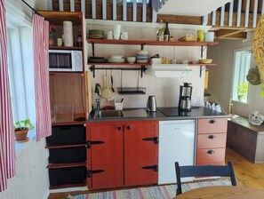 A compact kitchen with a microwave, coffee maker, and a refrigerator. - Cozy stone cottage on Gotlaand (Burgsvik)
