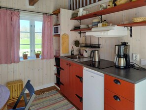 Eine Küche mit Holzschränken, einem Spülbecken, einer Kaffeemaschine und einem Fenster mit Vorhängen.