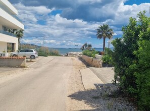 A coastal road leading to a building with a parked car. - Apartments Marija Sukosan - Classic One Bedroom Apartment (Sukosan)