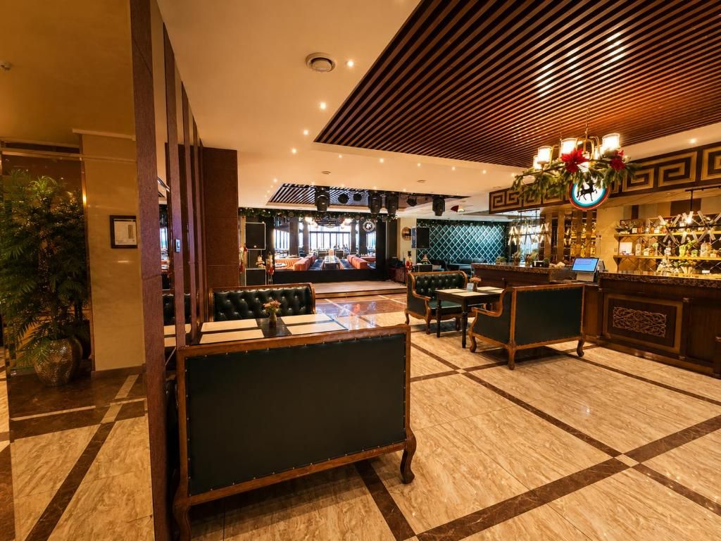 A hotel lobby with a bar area, seating arrangements, and a check-in desk.