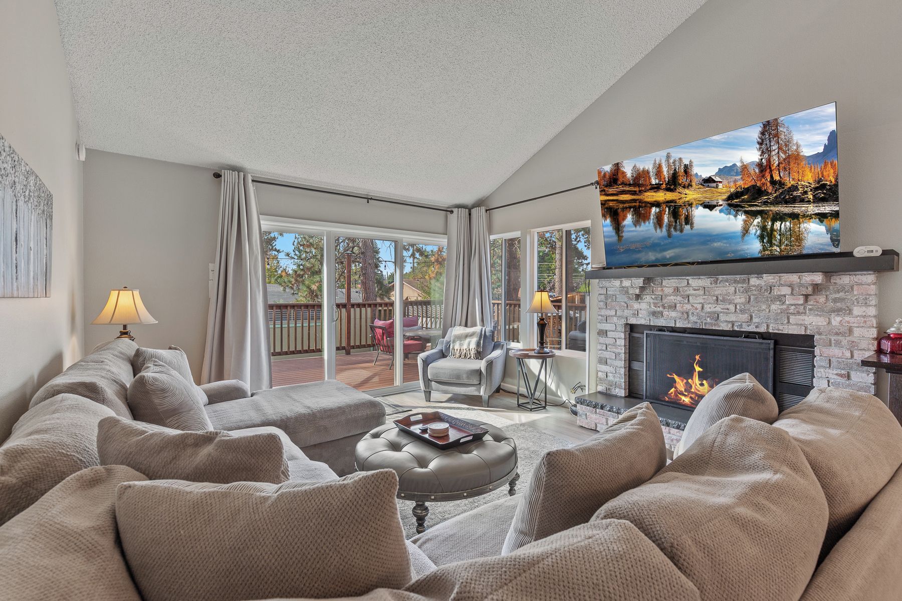 A living room with a fireplace, a sofa, a TV, and a view of a lake.