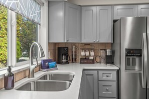 A modern kitchen with stainless steel appliances, a coffee station, and a view of the outdoors. - Your CDA Escape | Minutes to Downtown (Coeur D Alene)