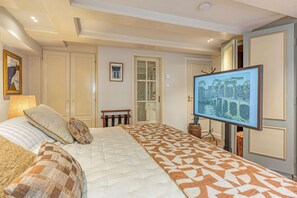 Ein Hotelzimmer mit Bett, Fernseher, Kamin und einer Tür zu einem weiteren Raum.
