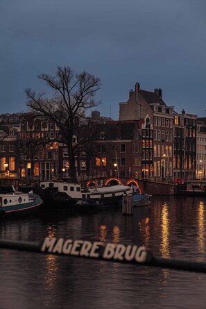 A waterfront view with traditional buildings, a bridge, and boats. - Amstel SeventyOne - River (Amsterdam)