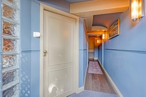 A hallway with a door, a light fixture, and a patterned rug. - Amstel SeventyOne - River (Amsterdam)