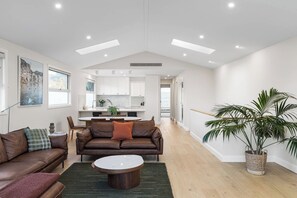 A modern living room with a brown leather sofa, a round coffee table, and a large potted plant. - Oakwood Retreat (Rosebud)
