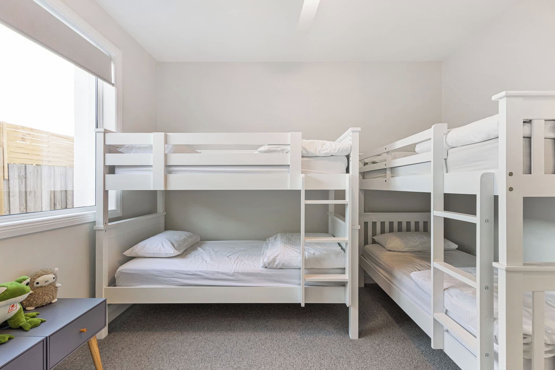 A bunk bed room with a desk and a window.