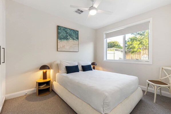 A bedroom with a bed, a ceiling fan, a window, and a painting. - Heated pool, Rosewood Oakwood  Retreat (Rosebud)
