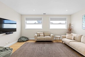 A modern living room with a flat-screen TV, two sofas, a coffee table, and a large rug. - Heated pool, Rosewood Oakwood  Retreat (Rosebud)