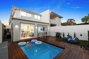 Ein modernes Haus mit Pool, überdachter Terrasse und umzäunter Garten.
