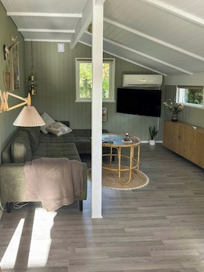 A spacious living room with a sectional sofa, a round coffee table, and a flat-screen TV mounted on the wall. - Holiday home with hot tub and orchard in Pøt (Hedensted)