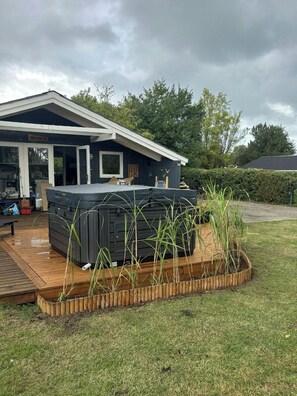 A house with a covered patio area, a hot tub, and a wooden deck. - Holiday home with hot tub and orchard in Pøt (Hedensted)
