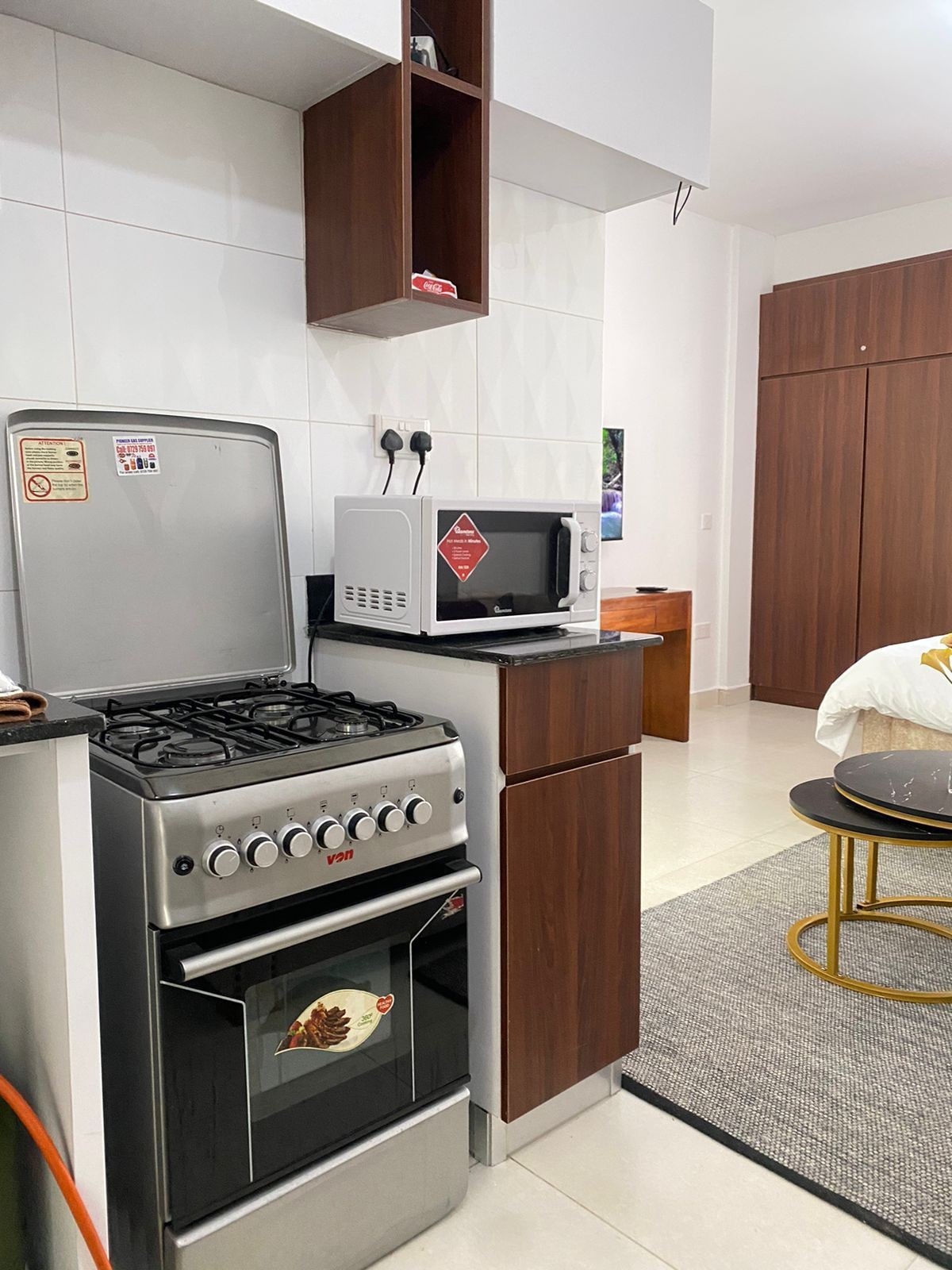 Uma cozinha compacta com fogão a gás, forno, micro-ondas e armários de madeira.
