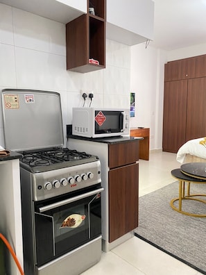 Uma cozinha compacta com fogão a gás, forno, micro-ondas e armários de madeira.
