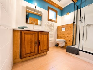 A bathroom with wooden cabinets, a toilet, a shower, and a window. - Charming Villa with Exceptional Views of the Lake (Esparron-de-Verdon)
