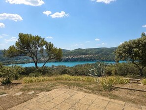 Uma área externa pavimentada com vista para um lago e colinas.